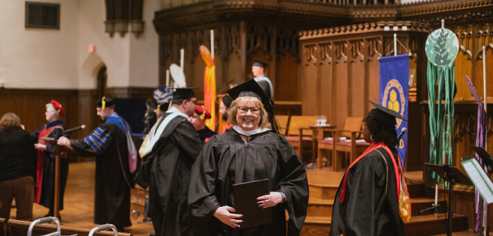 A photo of a United graduate during Commencement holding their diploma.