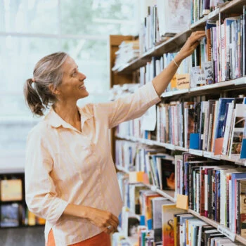 A person reaches for a book in the library.