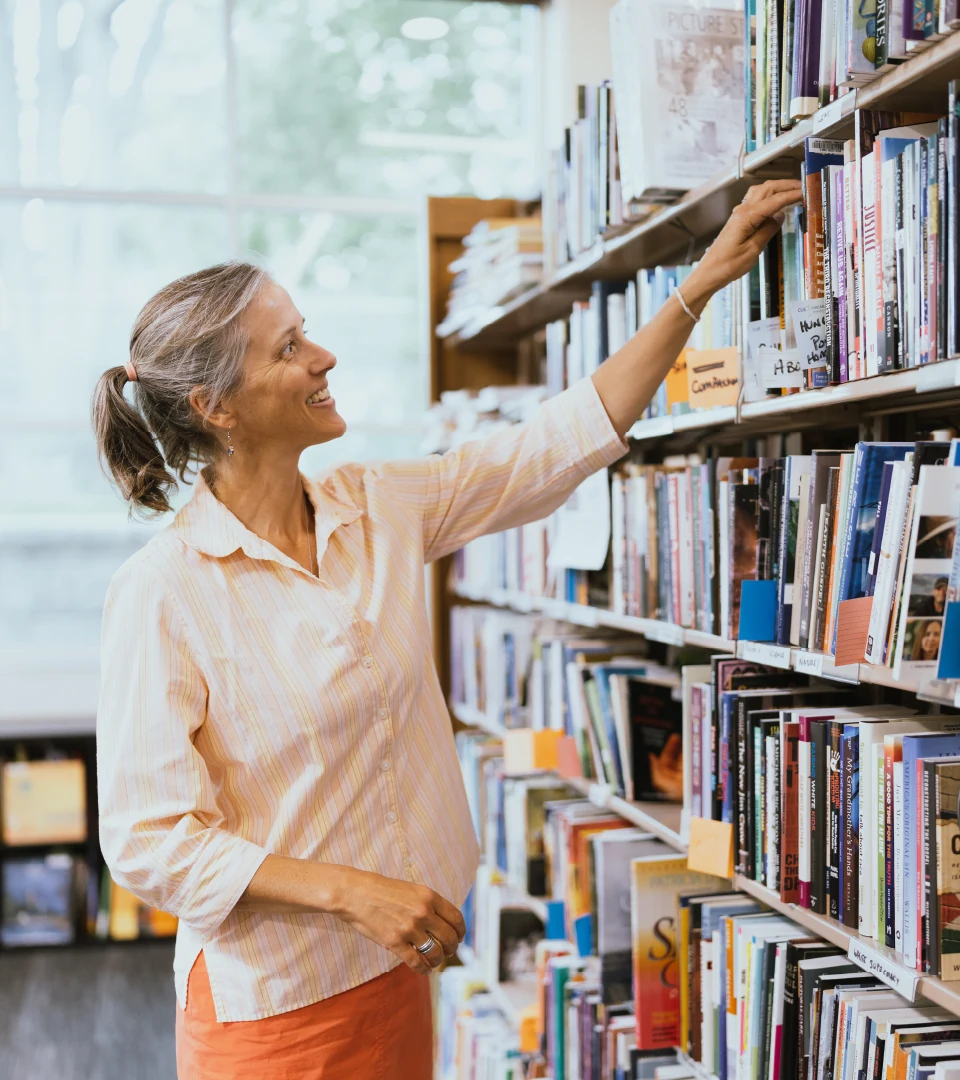 A person reaches for a book in the library.