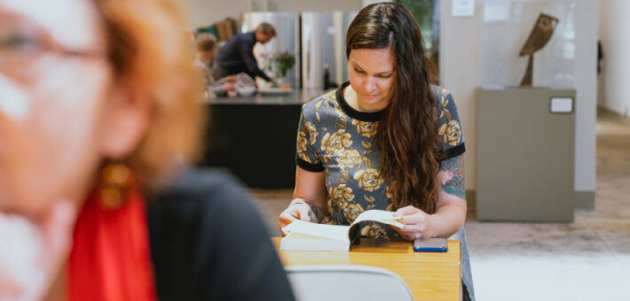 A student reads from a book on-campus.