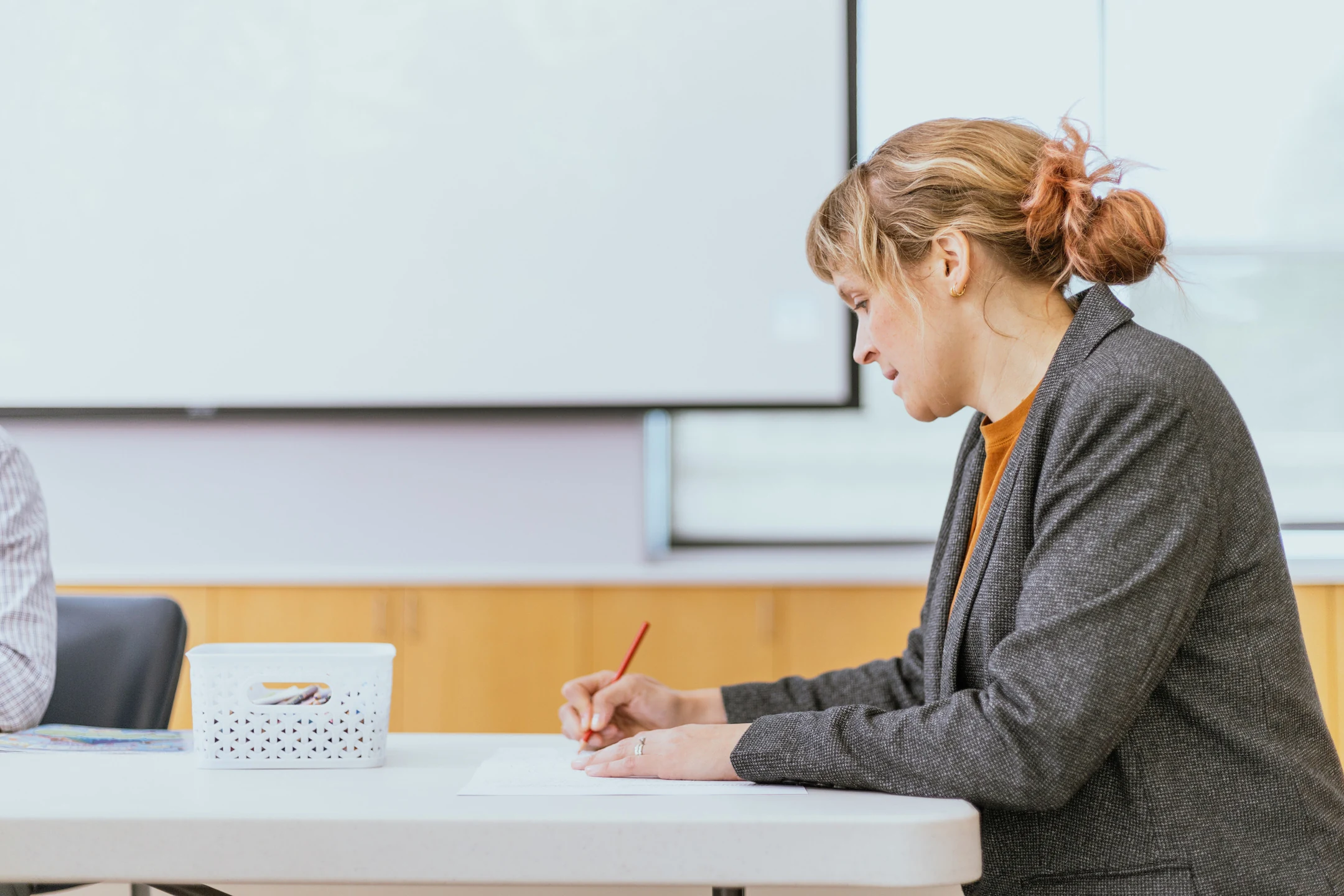 A United faculty member writes at a table.