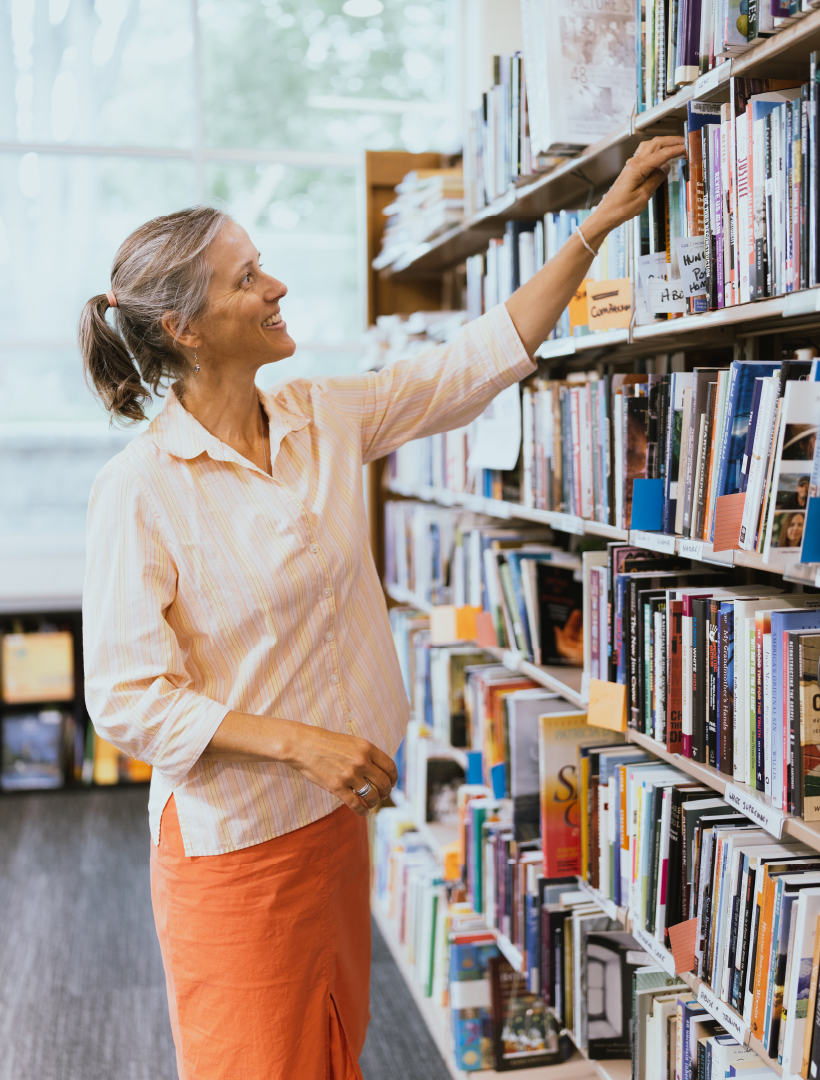 A photo of a person grabbing a book in the library.