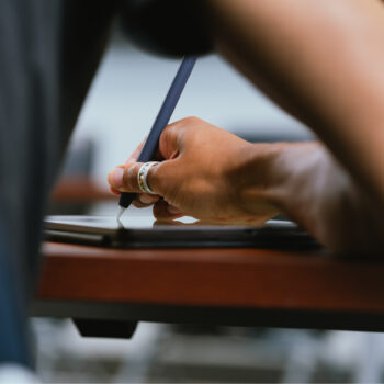 A photo of a student writing on a tablet.