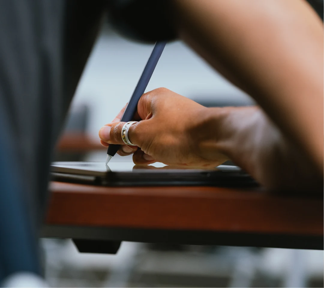 A photo of a student writing on a tablet.