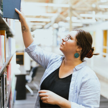 A photo of a student grabbing a book in the library.