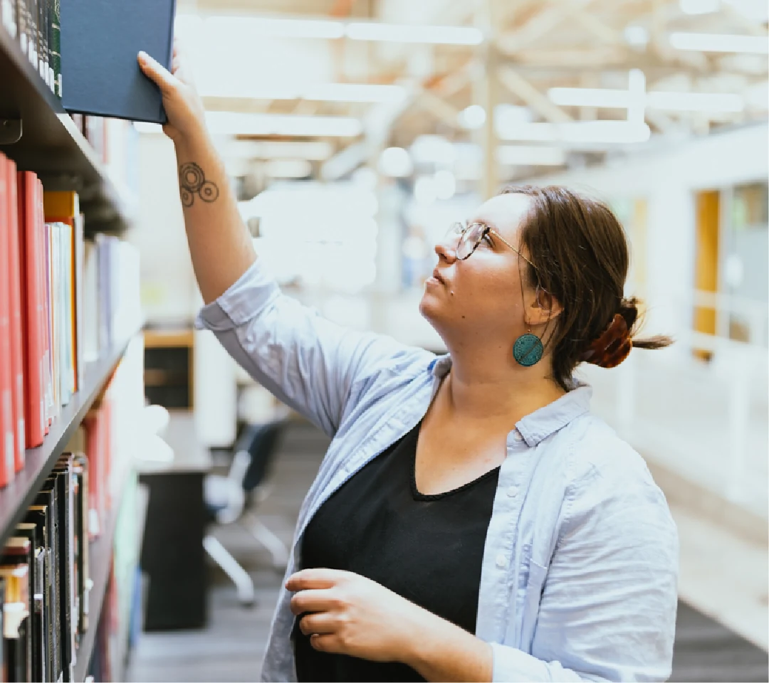 A photo of a student grabbing a book in the library.